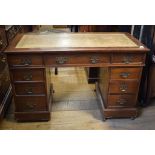 A George III style walnut pedestal desk, the leather inset top above an arrangement of nine drawers,