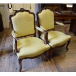 A pair of Louis XV style walnut armchairs, with carved decoration and yellow upholstery