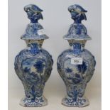 A pair of Dutch Delft vases, the covers with bird finials, the bases decorated dwellings, 34 cm high