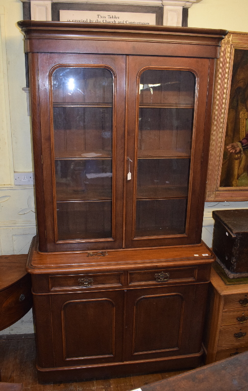 A late Victorian walnut bookcase on cupboard having a pair of glazed doors above two frieze drawers,