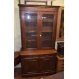 A late Victorian walnut bookcase on cupboard having a pair of glazed doors above two frieze drawers,