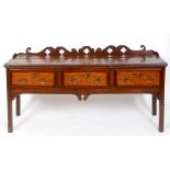 A George III oak dresser base, cross banded in mahogany, having three frieze drawers, on square legs