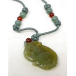 A Chinese carved and pierced jade pendant, in the form of a mythical animal on a fruit, the