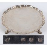 A George II silver salver, with a pie crust edge, on four scroll and shell feet, John Swift,