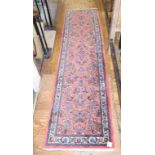 An Eastern runner, decorated flowers on a pink ground, within a multi border, 329 x 87 cm