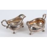 A pair of early 19th century silver sauce boats, with leaf capped scroll handles, on claw and ball