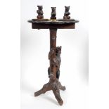 A late 19th/early 20th century Black Forest carved wood smokers stand, the top surmounted three