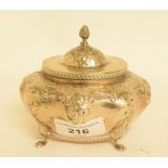 A late Victorian silver tea caddy, of shaped oval form, embossed flowers and foliage, on four pad