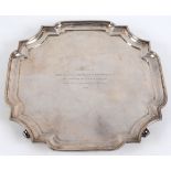 A silver salver, of shaped square form, with presentation inscription and dated 1932, on four scroll
