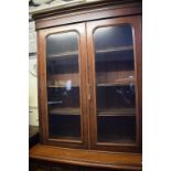 A late Victorian walnut bookcase on cupboard having a pair of glazed doors above two frieze drawers,