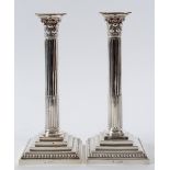 A pair of late Victorian silver Corinthian column table candlesticks, on stepped square bases with