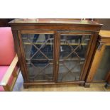 A glazed two door bookcase, with adjustable shelves, 114 cm wide