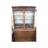 An early 20th century mahogany bookcase on cupboard, having a pair of bar glazed doors above a