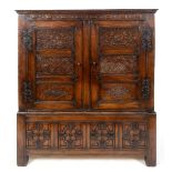An oak cupboard on stand, carved flowers and foliage, having a pair of panel doors, the base with