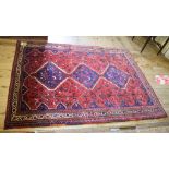 An Eastern rug, decorated central medallions, animal and floral motifs on a red ground, within a
