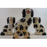 Five Staffordshire pottery spaniels, with black spots, the largest 25 cm high