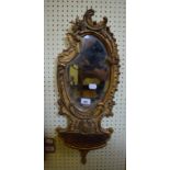 A pair of late Victorian gilt gesso wall mirrors, of shaped form, with shells below, 65 x 25 cm (2)