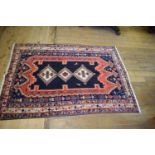 A Persian Afshr rug, decorated three central medallions on a dark blue ground, within a multi