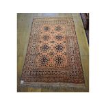 An Eastern rug, decorated floral motifs on a salmon pink ground, within a multi border, 200 x 125