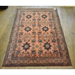 An Eastern rug, decorated animal and other motifs on a salmon pink ground, within a multi border,