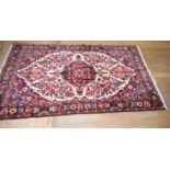 A Persian Borchalo rug, decorated flowers on a cream ground, with a central medallion, within a