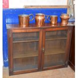 A walnut bookcase, with a pair of glazed doors, 122 cm wide, and four copper measures (5) Report