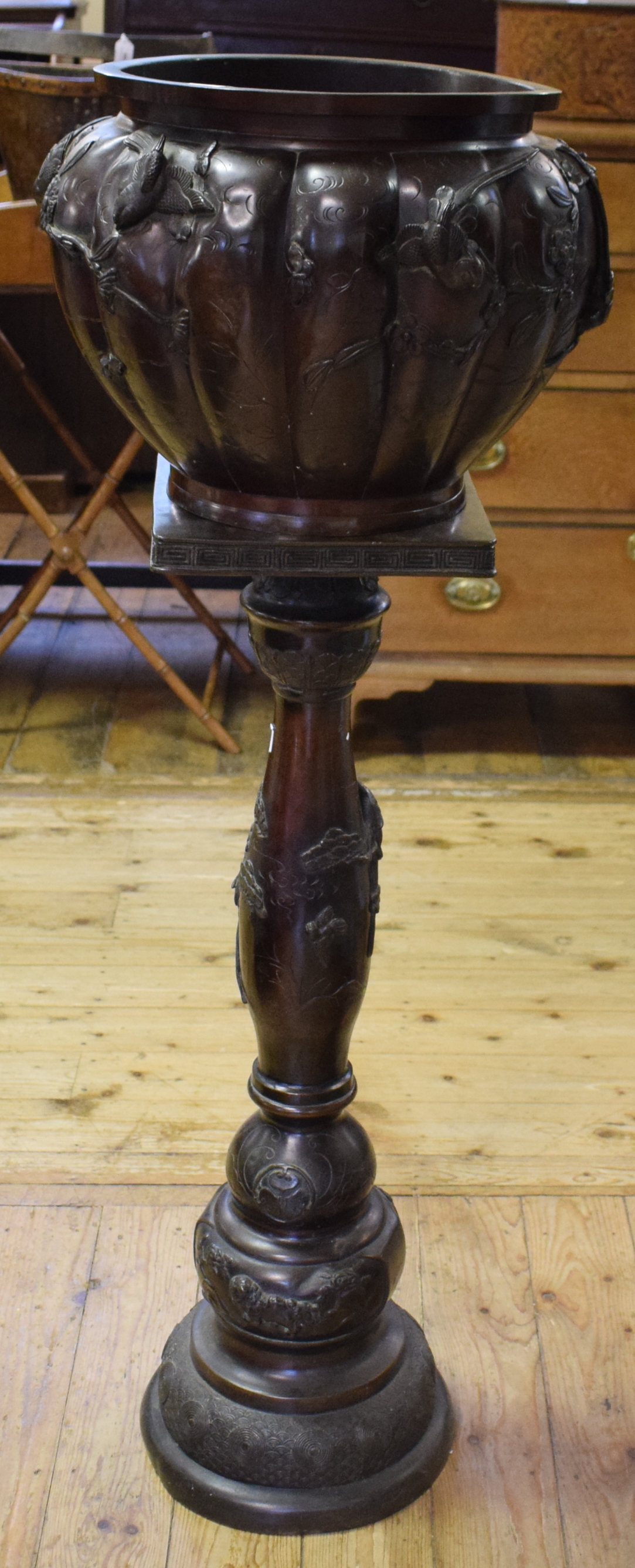 A Japanese bronze jardinere on stand, of shaped circular form, decorated in relief with birds and