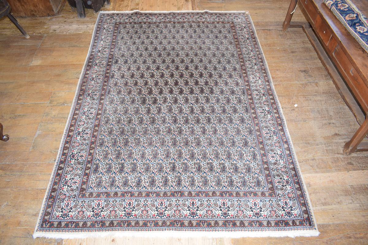 A Persian Moud carpet, decorated paisley motifs on a cream ground, within a multi border, 310 x