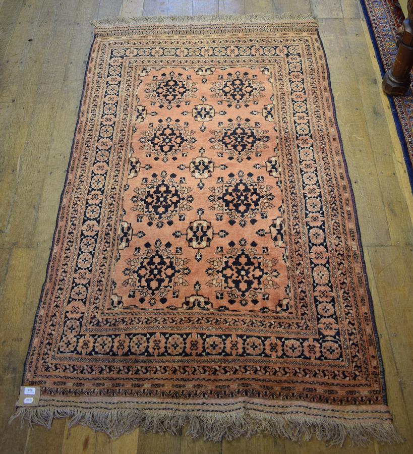 An Eastern rug, decorated floral motifs on a salmon pink ground, within a multi border, 200 x 125