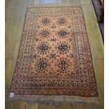 An Eastern rug, decorated floral motifs on a salmon pink ground, within a multi border, 200 x 125