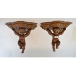 A pair of carved giltwood brackets, on cherub supports, 31 cm high (2) Later spray painted.