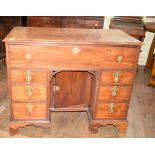 A mahogany kneehole desk, having a frieze drawer above a recess with a cupboard door, flanked by two