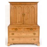 A stripped pine cabinet on chest, having a pair of lancet panel doors, above two short and two