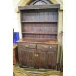 A stained pine dresser and plate rack, having two frieze drawers above a pair of panel doors, 125 cm