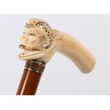 A walking cane, the L shaped walrus ivory handle in the form of a sailor with sulphur glass eyes