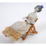 A porcelain half doll, lady with grey hair and a feather, wearing a fabric dress, complete with