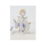 An Art Deco porcelain half doll, lady with blonde hair wearing a blouse with geometric decoration,