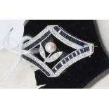 An 18ct white gold, sapphire and diamond brooch, of shaped lozenge form, centre with a pearl,