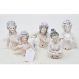 A porcelain half doll, nude lady with arms crossed, 11 cm high, and four others (5)