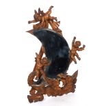 A crescent shape mirror, in a pine frame carved cherubs and a dragon, on a strut leg, 78 cm high See