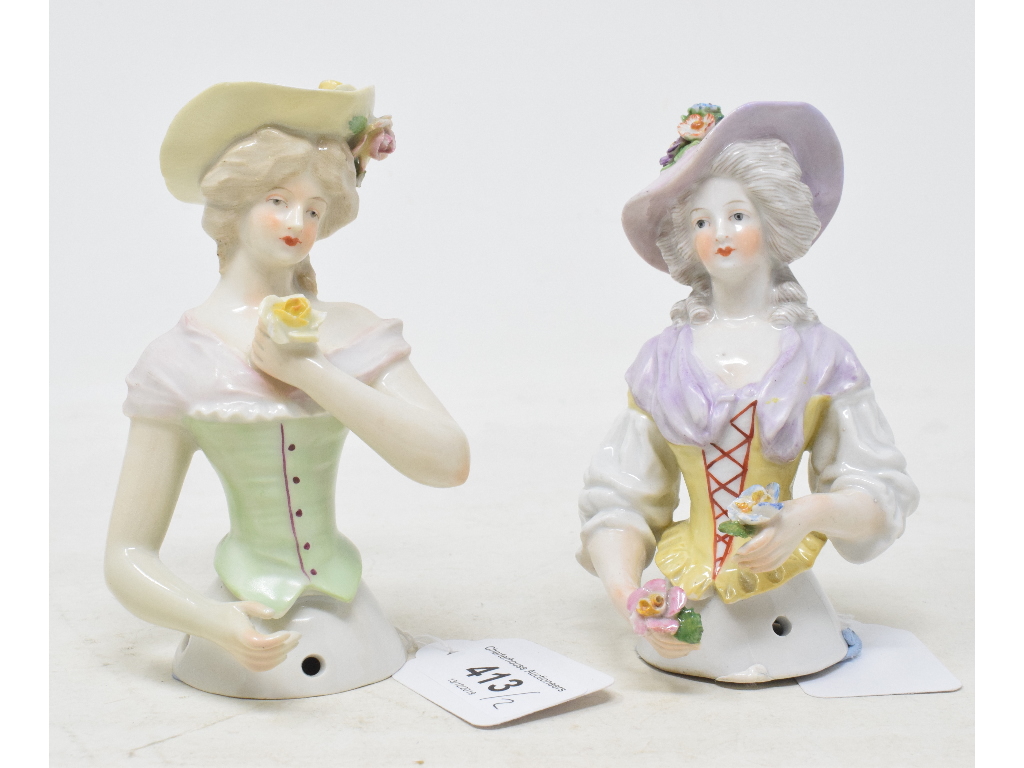 A porcelain half doll, lavender hat and scarf, holding flowers and wearing a yellow corset, 12 cm