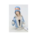 An Art Deco porcelain half doll, lady wearing a blue fir lined coat and matching hat, impressed