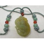 A Chinese carved and pierced jade pendant, in the form of a mythical animal on a fruit, the