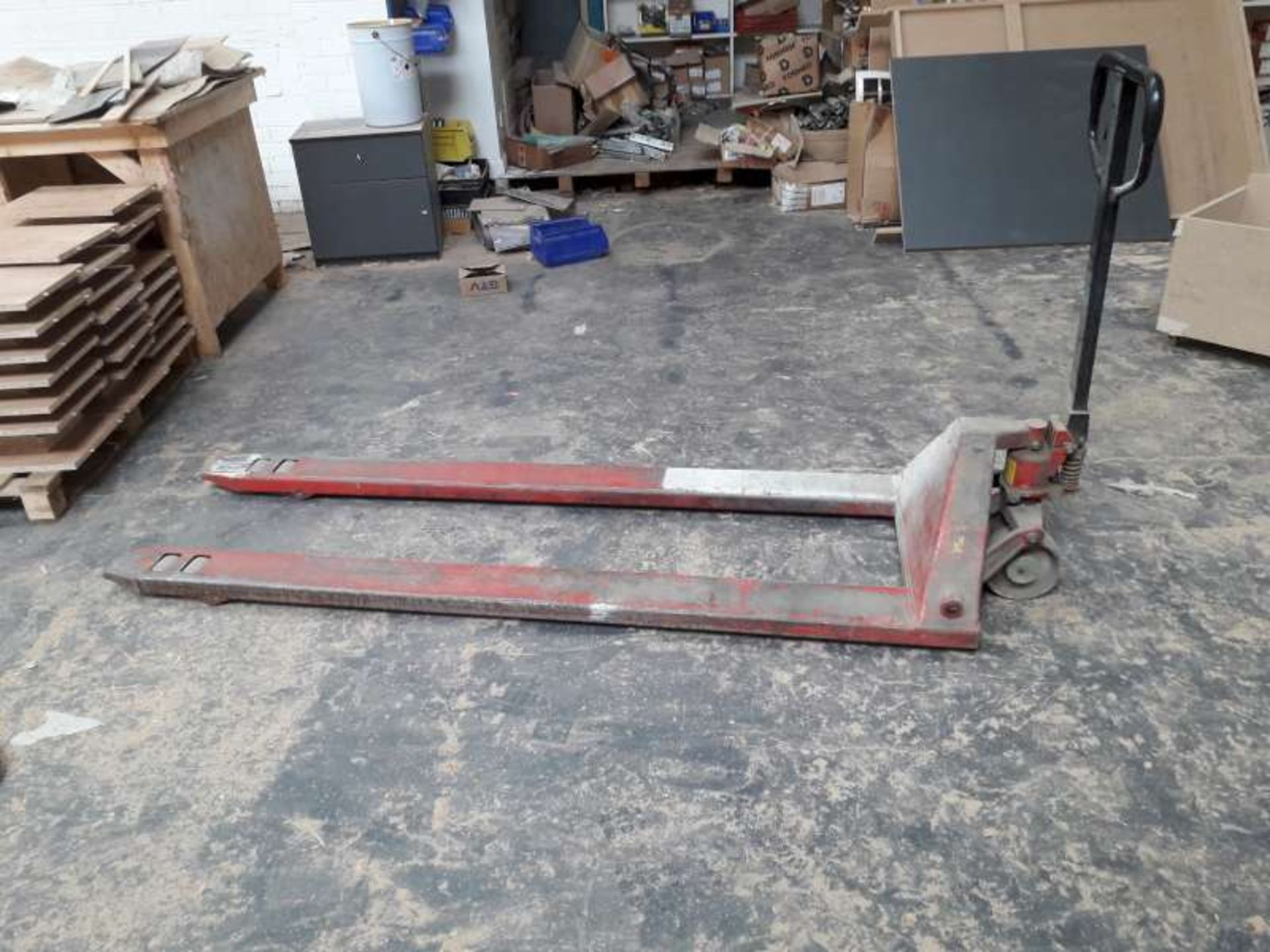 1 X RED PAINTED PALLET TRUCK WITH APPROX 7 FT FORKS.