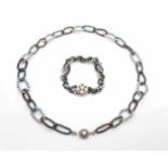 1 cultured pearl necklace and 1 bracelet with black and grey pearls. The locks are made of 585 white
