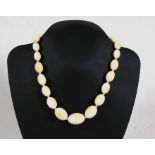 An early 20th century string of graduated oval ivory beads, 47cms (18.5ins) long.