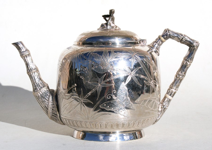 A Victorian silver plated Japanese manner teapot decorated with flowers, fans and insects, 17cms (