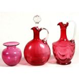 A Victorian cranberry glass decanter; together with a similar jug and a cranberry glass vase, the