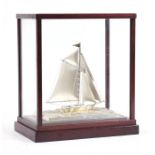 A Japanese sterling silver model of a yacht in a mahogany display case, 13cms (5.1ins) high, the