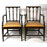 A pair of Edwardian mahogany elbow chairs with upholstered drop-in seats, on square tapering front